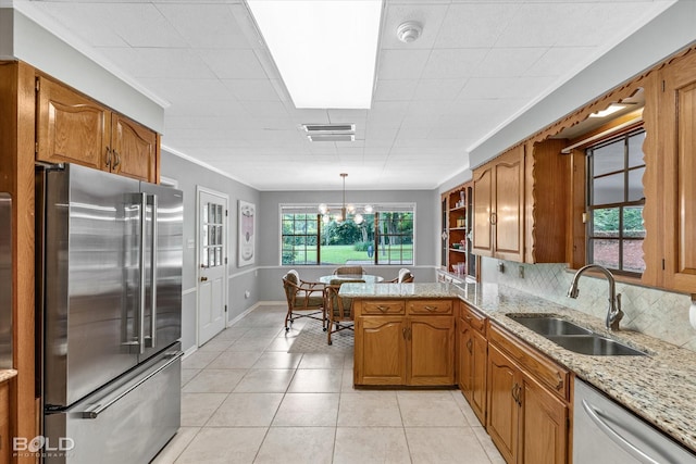 5918 Fern Ave, Shreveport, LA 71105 - kitchen featuring appliances with stainless steel finishes, a sink, brown cabinetry, light stone counters, and a peninsula