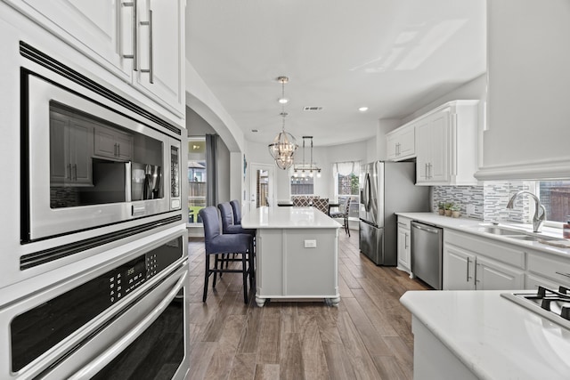 316 Cunningham Cir, Celina, TX 75009 - kitchen featuring appliances with stainless steel finishes, a chandelier, white cabinetry, a center island, and tasteful backsplash