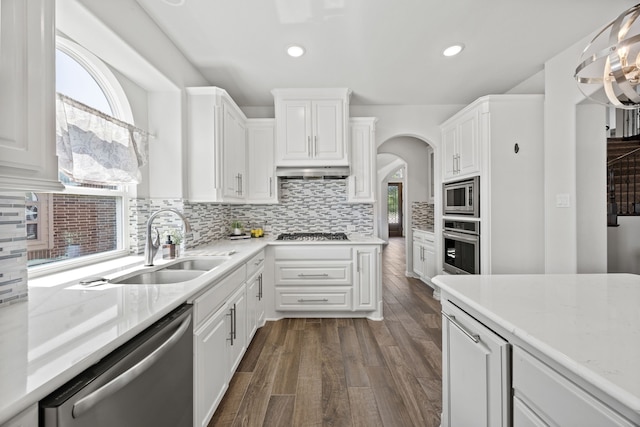 316 Cunningham Cir, Celina, TX 75009 - kitchen featuring appliances with stainless steel finishes, white cabinets, a sink, decorative backsplash, and arched walkways