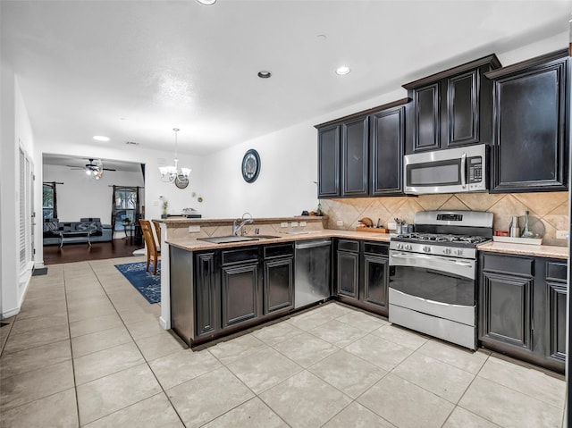 5605 Cojimar Dr, Mckinney, TX 75070 - kitchen featuring stainless steel appliances, dark cabinetry, a chandelier, a peninsula, and recessed lighting