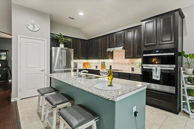 11521 Misty Mesa Dr, Fort Worth, TX 76052 - kitchen featuring stainless steel appliances, a sink, under cabinet range hood, light stone countertops, and lofted ceiling