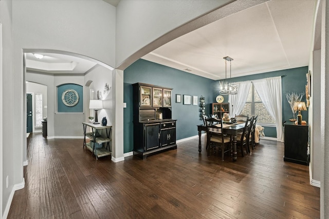 11521 Misty Mesa Dr, Fort Worth, TX 76052 - dining space with dark wood-style floors, arched walkways, baseboards, a chandelier, and a tray ceiling