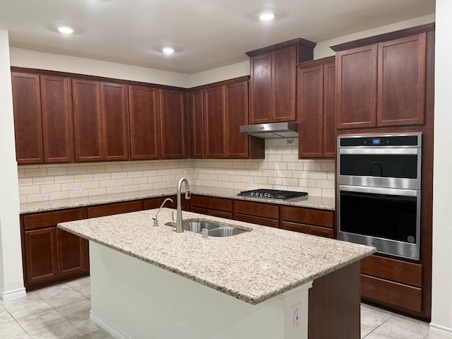 3681 Keechi Creek Dr, Celina, TX 75078 - kitchen with a sink, stainless steel appliances, under cabinet range hood, light stone counters, and a center island with sink