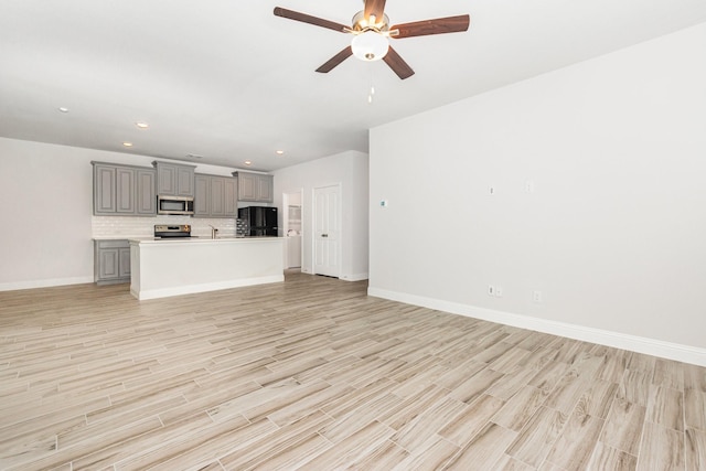 8409 Alba Ln, Rowlett, TX 75089 - unfurnished living room featuring light wood-type flooring, baseboards, ceiling fan, recessed lighting, and a sink