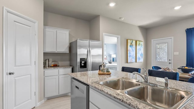 4212 Subtle Creek Ln, Fort Worth, TX 76036 - kitchen featuring appliances with stainless steel finishes, a sink, white cabinets, light wood-type flooring, and light stone countertops