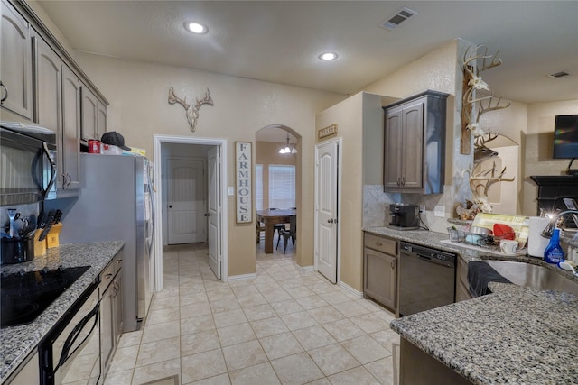 144 Brady Coleman Ln, Springtown, TX 76082 - kitchen with black appliances, arched walkways, light stone countertops, light tile patterned floors, and a sink
