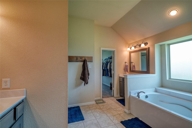 144 Brady Coleman Ln, Springtown, TX 76082 - bathroom with vanity, a garden tub, a spacious closet, tile patterned flooring, and lofted ceiling