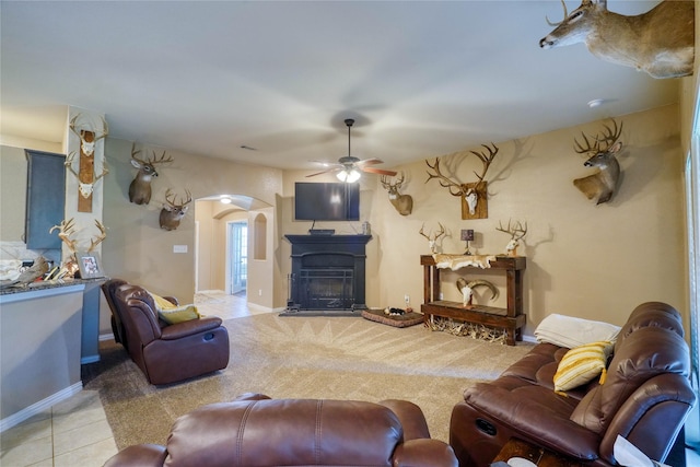144 Brady Coleman Ln, Springtown, TX 76082 - carpeted living room with a ceiling fan, arched walkways, a fireplace with raised hearth, tile patterned flooring, and baseboards