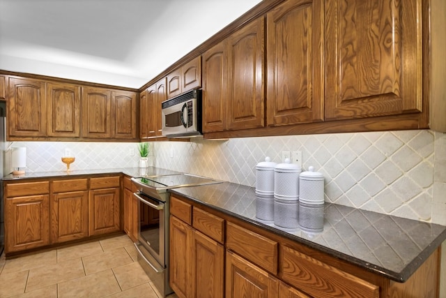 229 Maggie Cir, Flint, TX 75762 - kitchen featuring appliances with stainless steel finishes, light tile patterned floors, backsplash, dark countertops, and brown cabinets