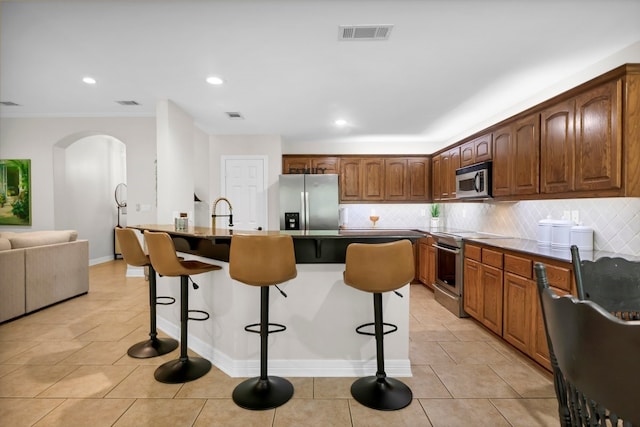 229 Maggie Cir, Flint, TX 75762 - kitchen featuring appliances with stainless steel finishes, arched walkways, a kitchen breakfast bar, decorative backsplash, and recessed lighting