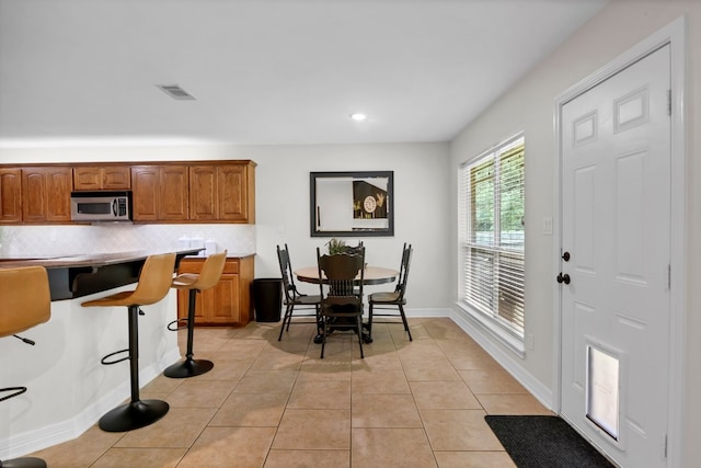 229 Maggie Cir, Flint, TX 75762 - kitchen with stainless steel microwave, decorative backsplash, brown cabinets, recessed lighting, and a breakfast bar area