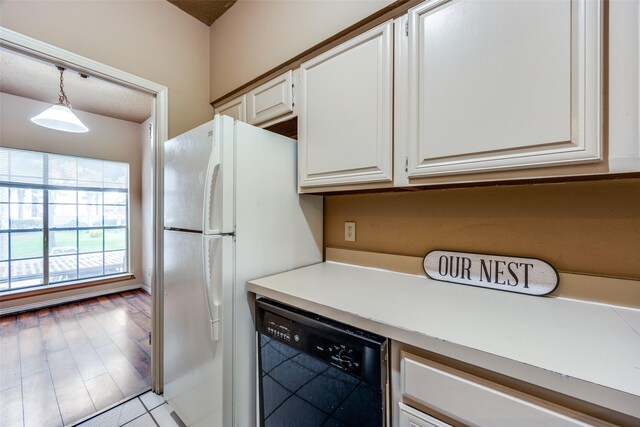 9801 Royal Ln Unit 703, Dallas, TX 75231 - kitchen featuring black dishwasher, white cabinetry, light countertops, freestanding refrigerator, and hanging light fixtures