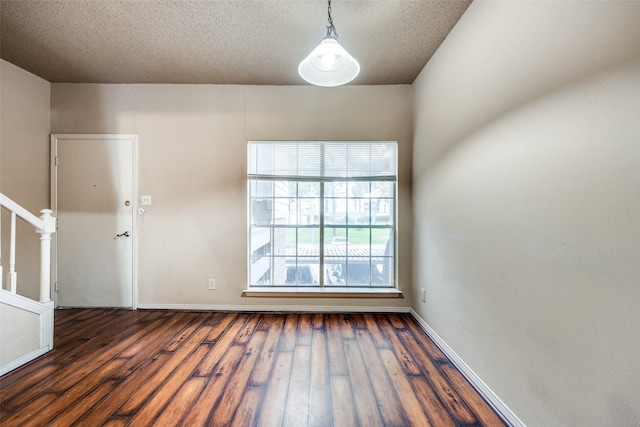 9801 Royal Ln Unit 703, Dallas, TX 75231 - unfurnished room featuring dark wood-style floors, stairway, a textured ceiling, and baseboards