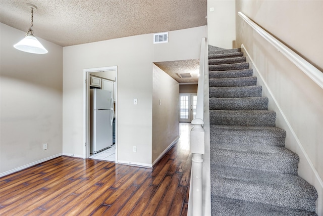 9801 Royal Ln Unit 703, Dallas, TX 75231 - stairs featuring wood finished floors, a textured ceiling, and baseboards