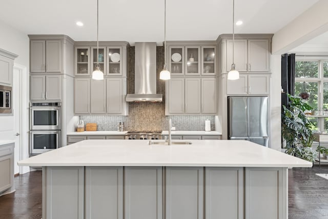 925 Glen Lake Dr, Southlake, TX 76092 - kitchen with stainless steel appliances, wall chimney range hood, gray cabinetry, backsplash, and an island with sink