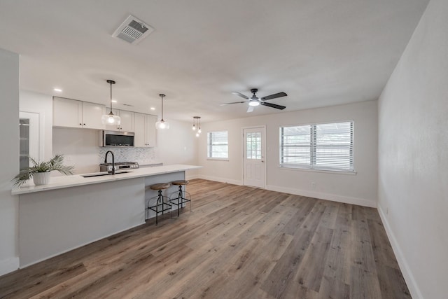 509 Twilight Dr, Garland, TX 75040 - kitchen with stainless steel microwave, a sink, light wood-style floors, backsplash, and baseboards