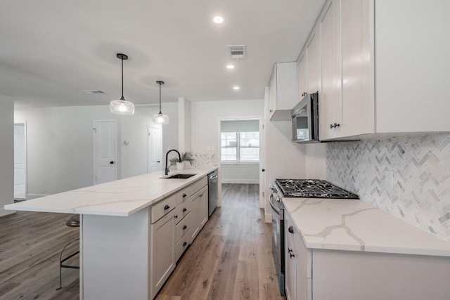 509 Twilight Dr, Garland, TX 75040 - kitchen with appliances with stainless steel finishes, a sink, light wood-style flooring, decorative backsplash, and a breakfast bar area