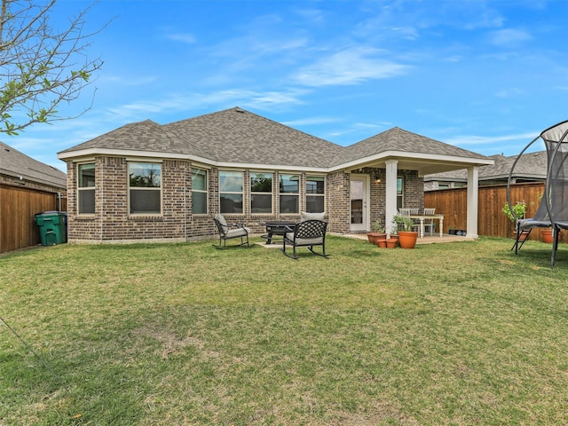 2624 Rambling Rd, Celina, TX 75009 - back of house with a trampoline, brick siding, a fenced backyard, and roof with shingles