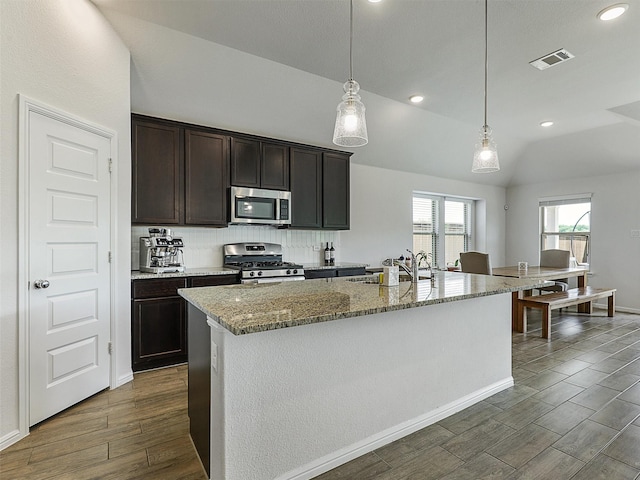 2624 Rambling Rd, Celina, TX 75009 - kitchen with stainless steel appliances, dark wood-type flooring, light stone counters, decorative light fixtures, and vaulted ceiling