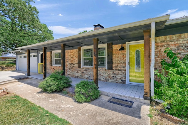 1229 Kiowa Dr E, Lake Kiowa, TX 76240 - doorway to property with a porch, a garage, concrete driveway, and brick siding