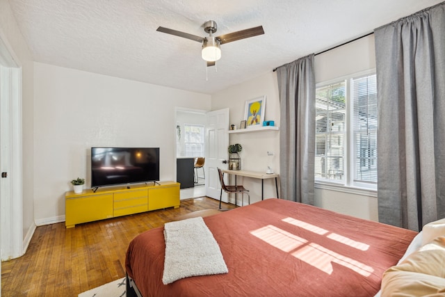 2435 W 10th St, Dallas, TX 75211 - bedroom featuring baseboards, hardwood / wood-style flooring, a textured ceiling, and a ceiling fan