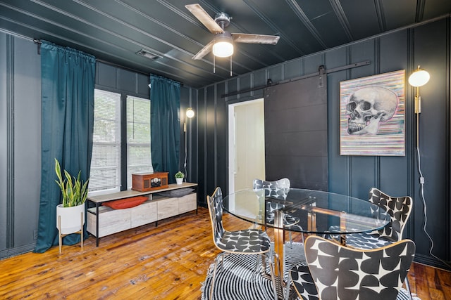 2435 W 10th St, Dallas, TX 75211 - dining room featuring a decorative wall, ceiling fan, hardwood / wood-style floors, and a barn door