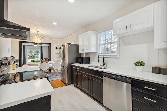 2435 W 10th St, Dallas, TX 75211 - kitchen with stainless steel appliances, a sink, exhaust hood, white cabinetry, and light wood finished floors