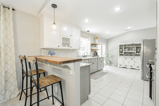806 Twin View St, Heath, TX 75032 - kitchen with freestanding refrigerator, vaulted ceiling, a peninsula, a kitchen bar, and tasteful backsplash
