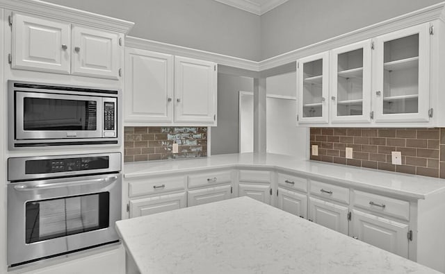 3009 Chimney Hill Dr, Waco, TX 76708 - kitchen featuring stainless steel appliances, crown molding, white cabinetry, glass insert cabinets, and decorative backsplash