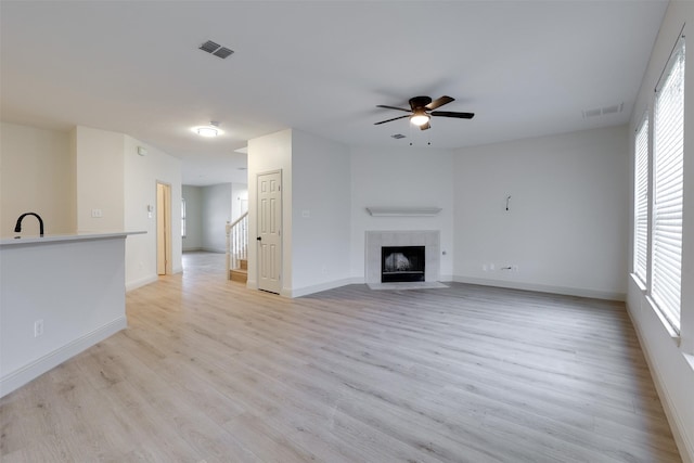 3037 Elmbrook Dr, Grand Prairie, TX 75052 - unfurnished living room with ceiling fan, a sink, light wood-style flooring, baseboards, and a fireplace