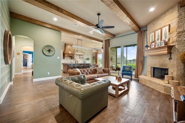 134 Southern Ct, Springtown, TX 76082 - living room featuring a ceiling fan, beamed ceiling, arched walkways, dark wood-type flooring, and a fireplace