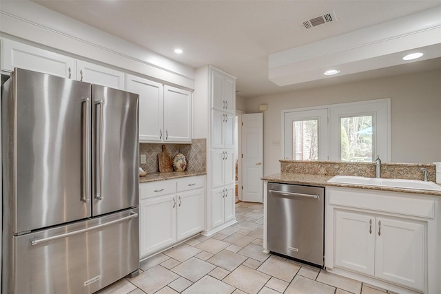 8921 Crest Ridge Dr, Fort Worth, TX 76179 - kitchen featuring appliances with stainless steel finishes, a sink, tasteful backsplash, white cabinetry, and recessed lighting