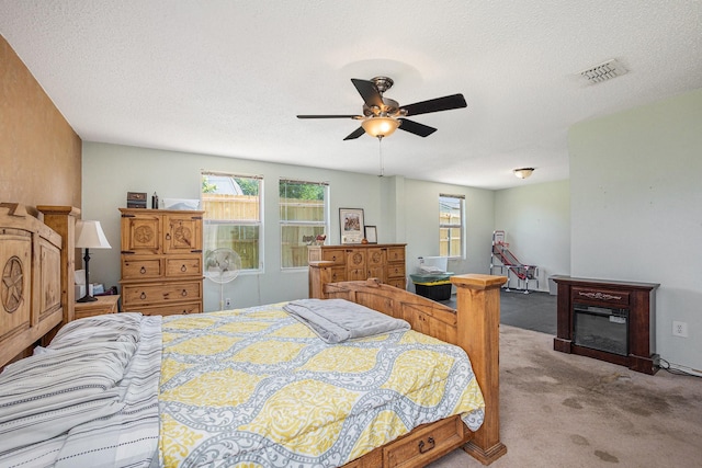 1400 Sunflower Ct, Burleson, TX 76028 - carpeted bedroom featuring a glass covered fireplace, a ceiling fan, and a textured ceiling