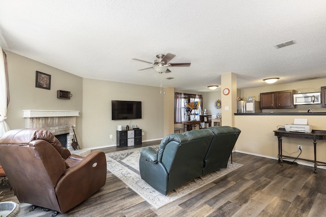 1400 Sunflower Ct, Burleson, TX 76028 - living room featuring ceiling fan, dark wood-style floors, a textured ceiling, a brick fireplace, and baseboards