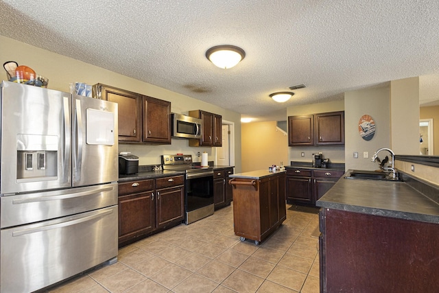 1400 Sunflower Ct, Burleson, TX 76028 - kitchen with stainless steel appliances, a sink, dark countertops, a textured ceiling, and dark brown cabinetry