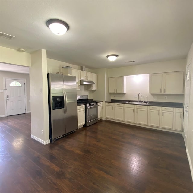 313 Wall St, Terrell, TX 75160 - kitchen featuring appliances with stainless steel finishes, a sink, under cabinet range hood, dark countertops, and dark wood-style flooring