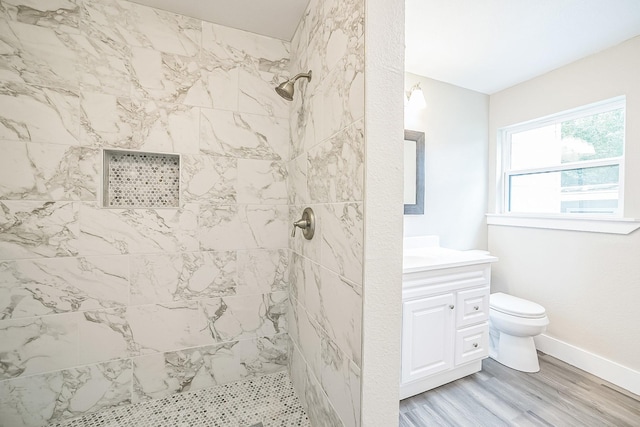 841 20th St SE, Paris, TX 75460 - full bath featuring wood finished floors, toilet, a tile shower, vanity, and baseboards