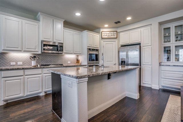 1137 Olympic Dr, Celina, TX 75009 - kitchen with appliances with stainless steel finishes, dark wood-style floors, stone countertops, white cabinets, and decorative backsplash