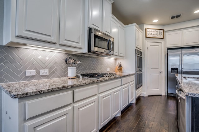 1137 Olympic Dr, Celina, TX 75009 - kitchen featuring appliances with stainless steel finishes, white cabinetry, dark wood-type flooring, light stone countertops, and tasteful backsplash