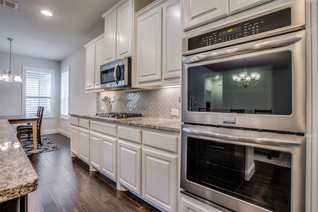 1137 Olympic Dr, Celina, TX 75009 - kitchen with a chandelier, appliances with stainless steel finishes, baseboards, dark wood finished floors, and backsplash