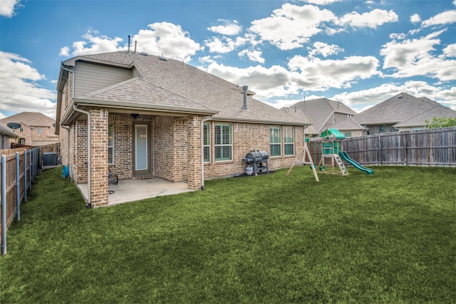 1137 Olympic Dr, Celina, TX 75009 - back of house with brick siding, a patio, a shingled roof, a playground, and cooling unit