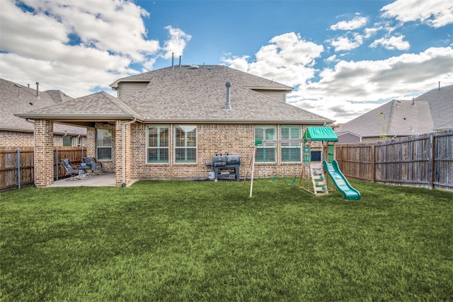 1137 Olympic Dr, Celina, TX 75009 - back of property featuring a playground, a shingled roof, a patio area, and brick siding
