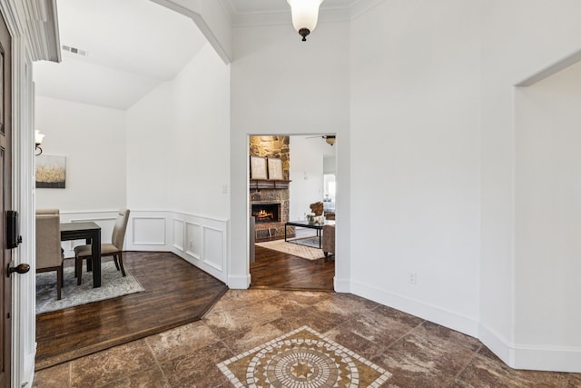 3076 W Alamosa Dr, Terrell, TX 75160 - entryway with a high ceiling, a stone fireplace, ornamental molding, and a wainscoted wall