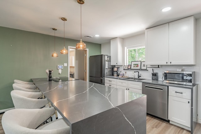 6812 Cumberland Rd, Fort Worth, TX 76116 - kitchen featuring appliances with stainless steel finishes, a sink, white cabinets, light wood-style flooring, and backsplash