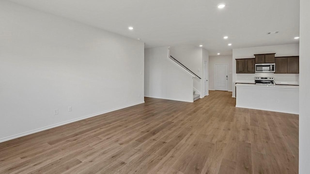 434 Drake Dr, Ferris, TX 75125 - unfurnished living room with recessed lighting, light wood finished floors, and stairs