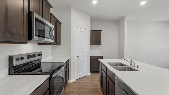 434 Drake Dr, Ferris, TX 75125 - kitchen with appliances with stainless steel finishes, wood finished floors, recessed lighting, dark brown cabinetry, and light countertops