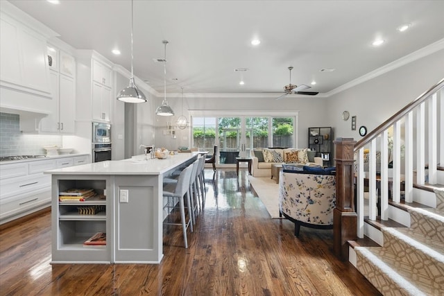 3770 W 5th St, Fort Worth, TX 76107 - kitchen featuring appliances with stainless steel finishes, dark wood-style flooring, an island with sink, ceiling fan, and ornamental molding