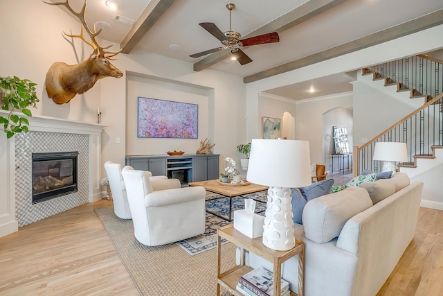 604 Rockfall Way, Aledo, TX 76008 - living room featuring light wood-type flooring, beam ceiling, stairway, arched walkways, and a tiled fireplace