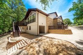 303 Llano Bnd, Holly Lake Ranch, TX 75765 - rear view of house with stairs, stucco siding, a garage, and concrete driveway
