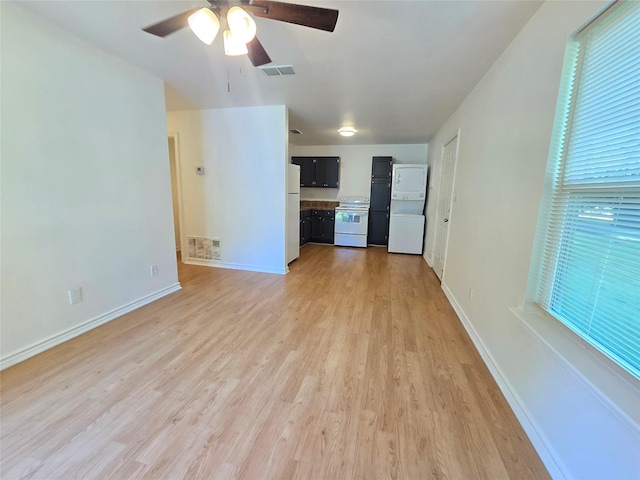 201 Paschal, Troup, TX 75789 - unfurnished living room featuring stacked washer / dryer, light wood-type flooring, ceiling fan, and baseboards